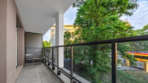 Ein Balkon mit Blick auf Bäume und Gebäude, ein Stuhl und ein Tisch.