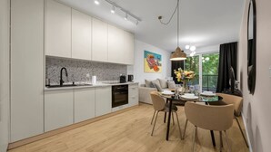 Eine moderne Küche mit weißen Schränken, ein Essbereich mit Tisch und Stühlen sowie eine Wohnbereich mit einer Couch.