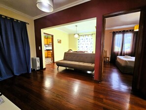 Ein Wohnzimmer mit einer Couch, ein Essbereich mit Tisch und Stühlen sowie eine durch einen offenen Durchgang sichtbare Küche.