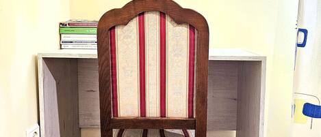 A corner desk with a chair, a stack of books, and a curtain.