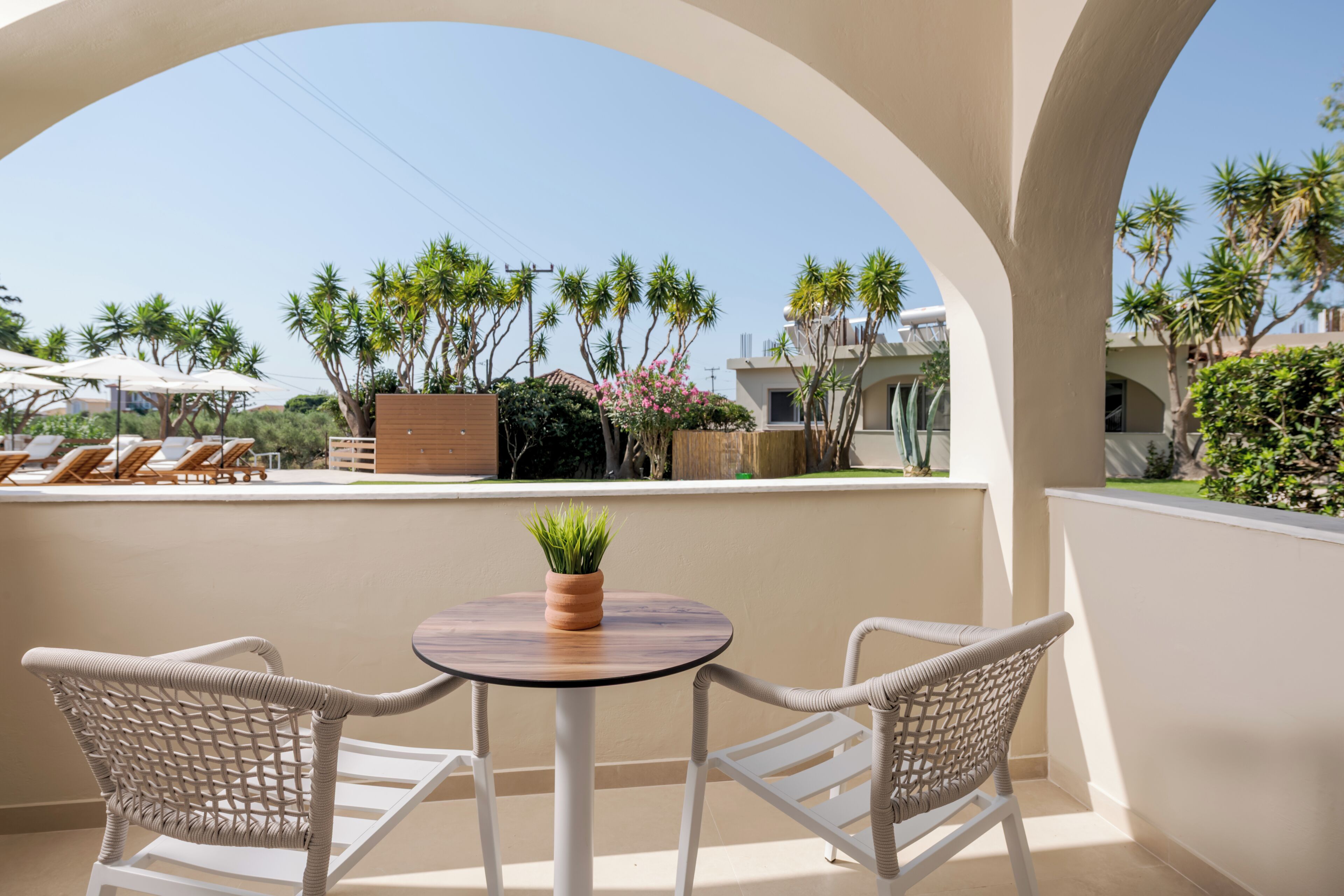 A balcony with two wicker chairs, a small round table, and a potted plant.