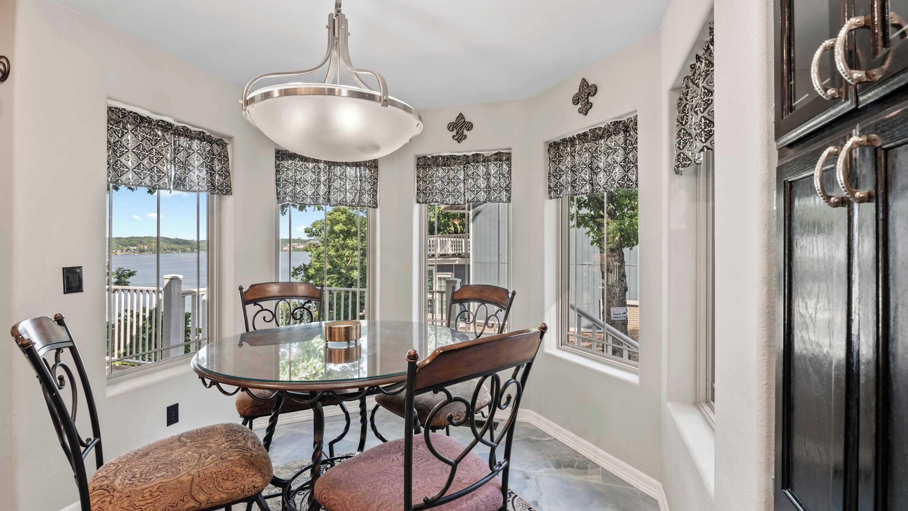 A dining area with a round table and chairs, a chandelier, and patterned window treatments.