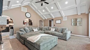 A spacious living room with a large sectional sofa, a ceiling fan, and a kitchen visible through an archway. - Riviera Paradise Lake Luxury (Sunrise Beach)