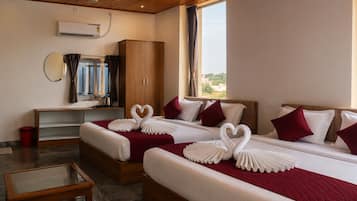 Una habitación de hotel con dos camas, un armario de madera, un escritorio con espejo y una ventana con cortinas.