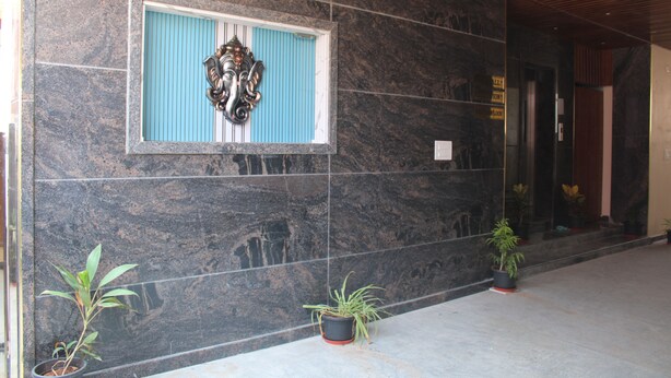 A lobby with dark marble walls, a framed artwork, and potted plants. - JP Residency (Tiruvannamalai)