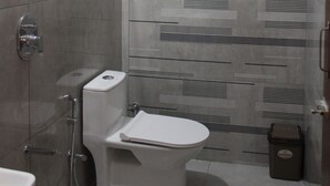 A bathroom with a shower, toilet, and a wall-mounted heater. - JP Residency (Tiruvannamalai)