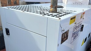 Uma unidade grande de ar condicionado industrial com etiquetas de segurança e um aviso.