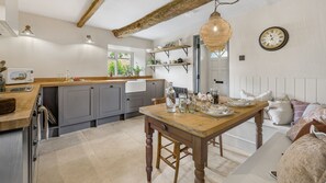 A kitchen with grey cabinets, a wooden table set for dining, and a hanging light fixture. - Rose Cottage Oddington - Countryside  Retreat, 2 bedroom, Lower Oddington (Oddington)