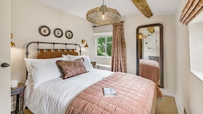 A bedroom with a bed, a bedside table, a mirror, and a window with curtains. - Rose Cottage Oddington - Countryside  Retreat, 2 bedroom, Lower Oddington (Oddington)