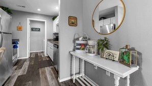 A modern kitchen with a white countertop, a coffee maker, and a decorative mirror. - Spruce Valley Condo 3bdr (Branson)