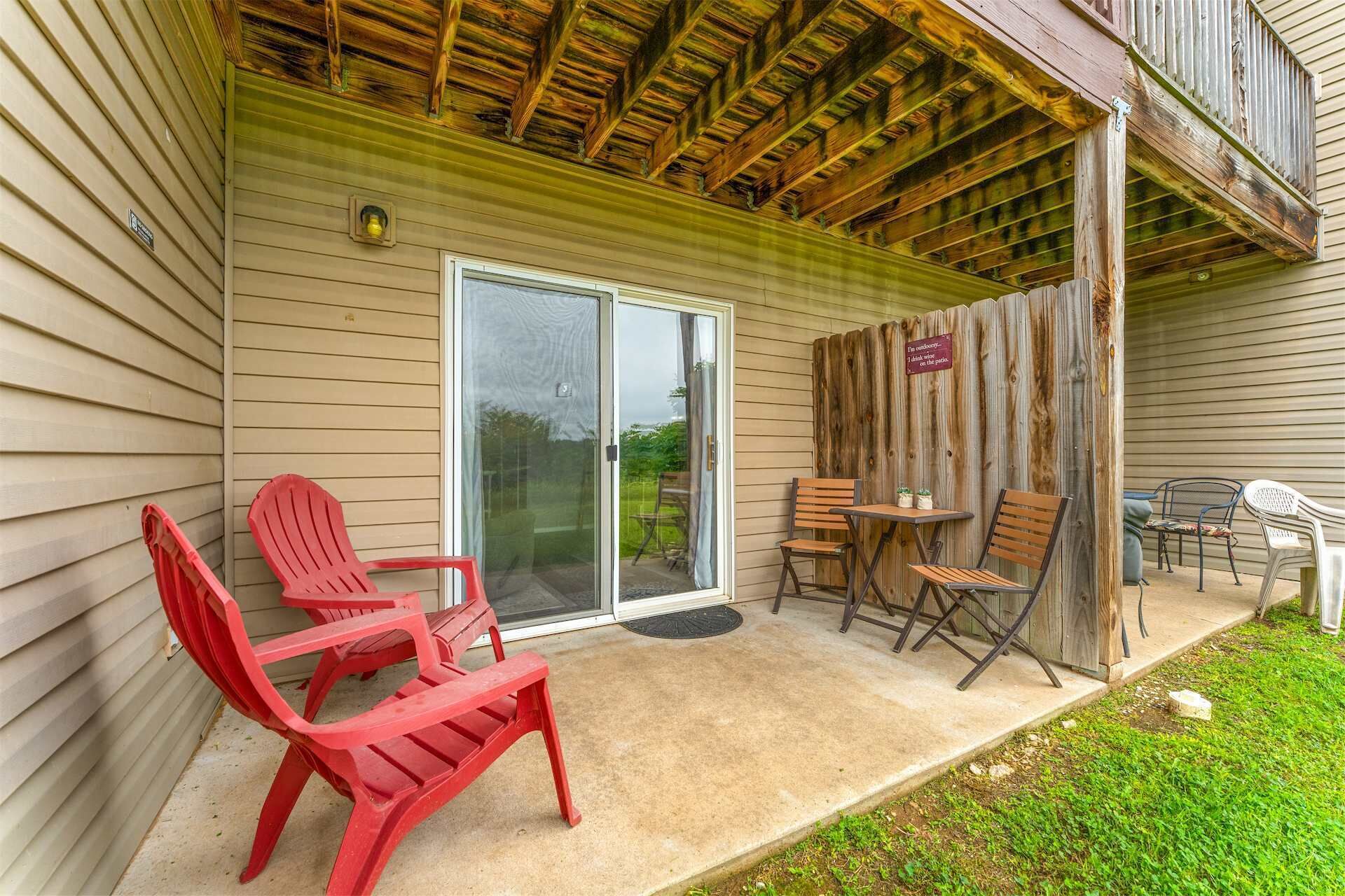 Une terrasse couverte avec des chaises rouges, une table et une clôture en bois.
