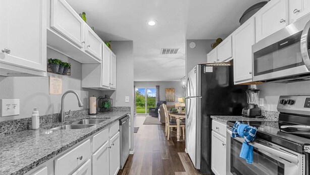 A modern kitchen with white cabinets, granite countertops, a stainless steel refrigerator, and a built-in oven. - Spruce Valley Condo 3bdr (Branson)