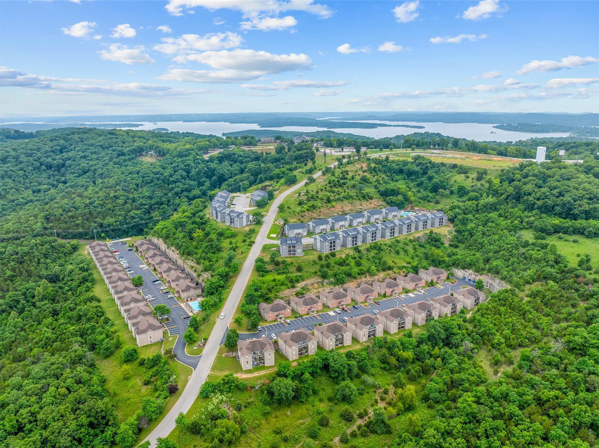 An aerial view of a residential area with multiple apartment complexes, roads, and surrounding greenery.