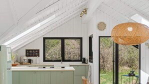 A kitchen with a large island, a hanging light fixture, and a view of the outdoors. - 4 Star Holiday Home in Rorvig (Rørvig)