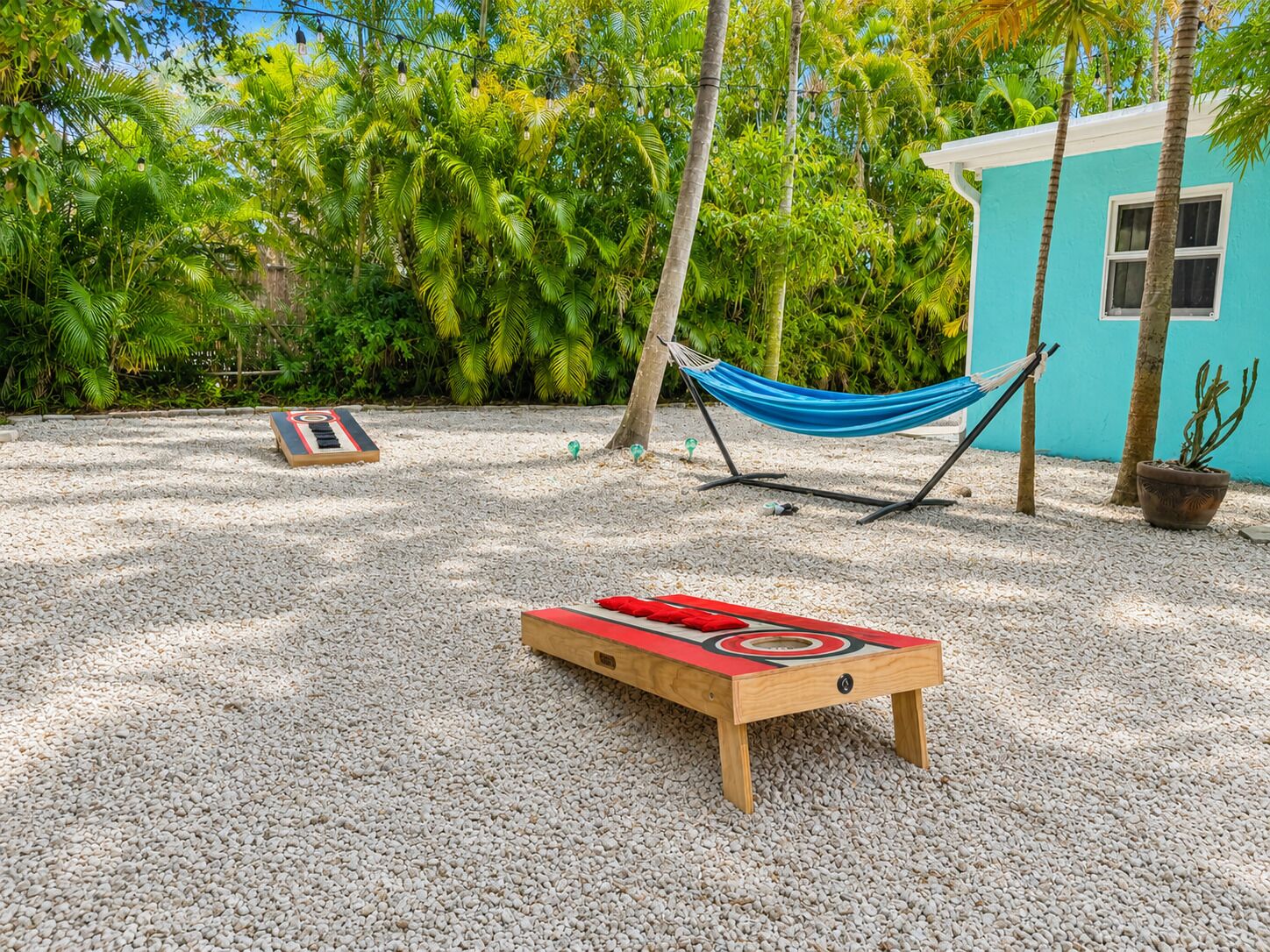 A hammock, a wooden board game, and a small building with a blue exterior.