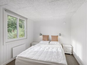 Ein Schlafzimmer mit einem großen Bett, zwei Nachttischen, einem Fenster und einer Heizung.