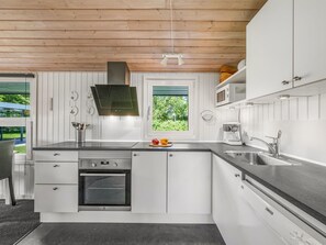 A modern kitchen with white cabinetry, a built-in oven, a microwave, and a large window. - "Wigman" - 450m to the fjord by Interhome (Tarm)
