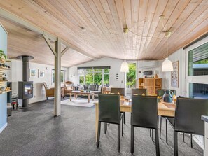 Ein großzügiger Wohnbereich mit hoher Decke, Kamin und Essbereich mit zeitgemäßer Einrichtung.
