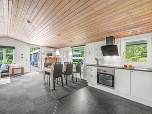 Eine moderne Küche mit Holzboden, eine Essecke mit Stühlen und Blick ins Grüne.