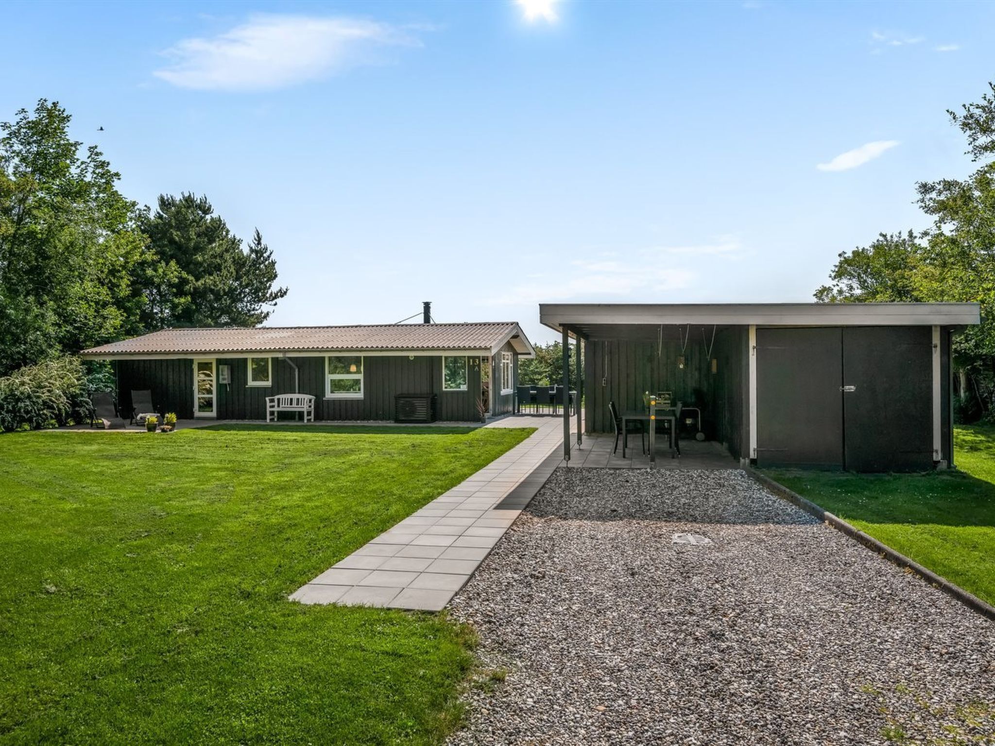 Een modern huis met een verharde oprit die leidt naar een overdekt terras.