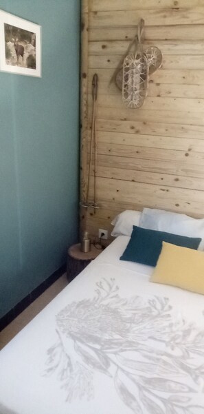 A bedroom with a bed, pillows, a wall-mounted light fixture, and a framed picture.