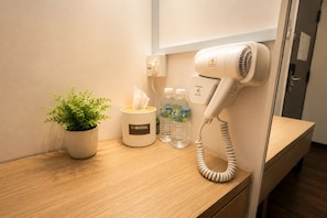 A hotel room with a bedside table, a hairdryer, a tissue box, and a potted plant. - H Hotel Segamat (Segamat)