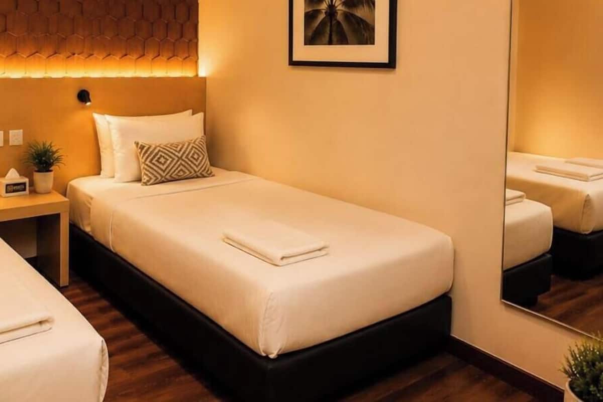 Una habitación de hotel con cama, mesita de noche y espejo.