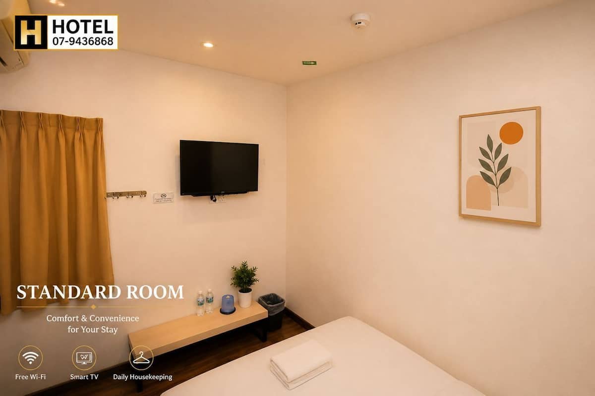 Una habitación de hotel estándar con una cama, televisión, planta y una obra de arte enmarcada en la pared.