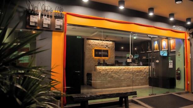 A hotel reception with a stone wall, a bench outside, and a sign above the entrance.