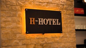 A sign with the text 'H-HOTEL' mounted on a stone wall.