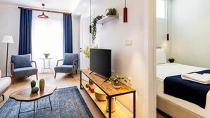 A modern hotel room with a sofa, two armchairs, a TV, a wooden side table, and a bed. - Gorgeous 3 Bedroom Apartment At Monnas Suite (Istanbul)