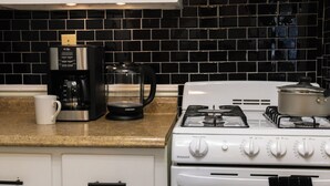 A kitchen with a gas stove, a coffee maker, and a kettle.