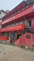 A building with a red facade and the sign 'HOTEL ASTHA' indicating it is a hotel.