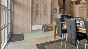 Ein moderner Essbereich mit Holzwänden, einem zentralen Tisch und schwarzen Stühlen.