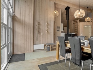 Un comedor moderno con paredes de madera, una mesa central y sillas negras.