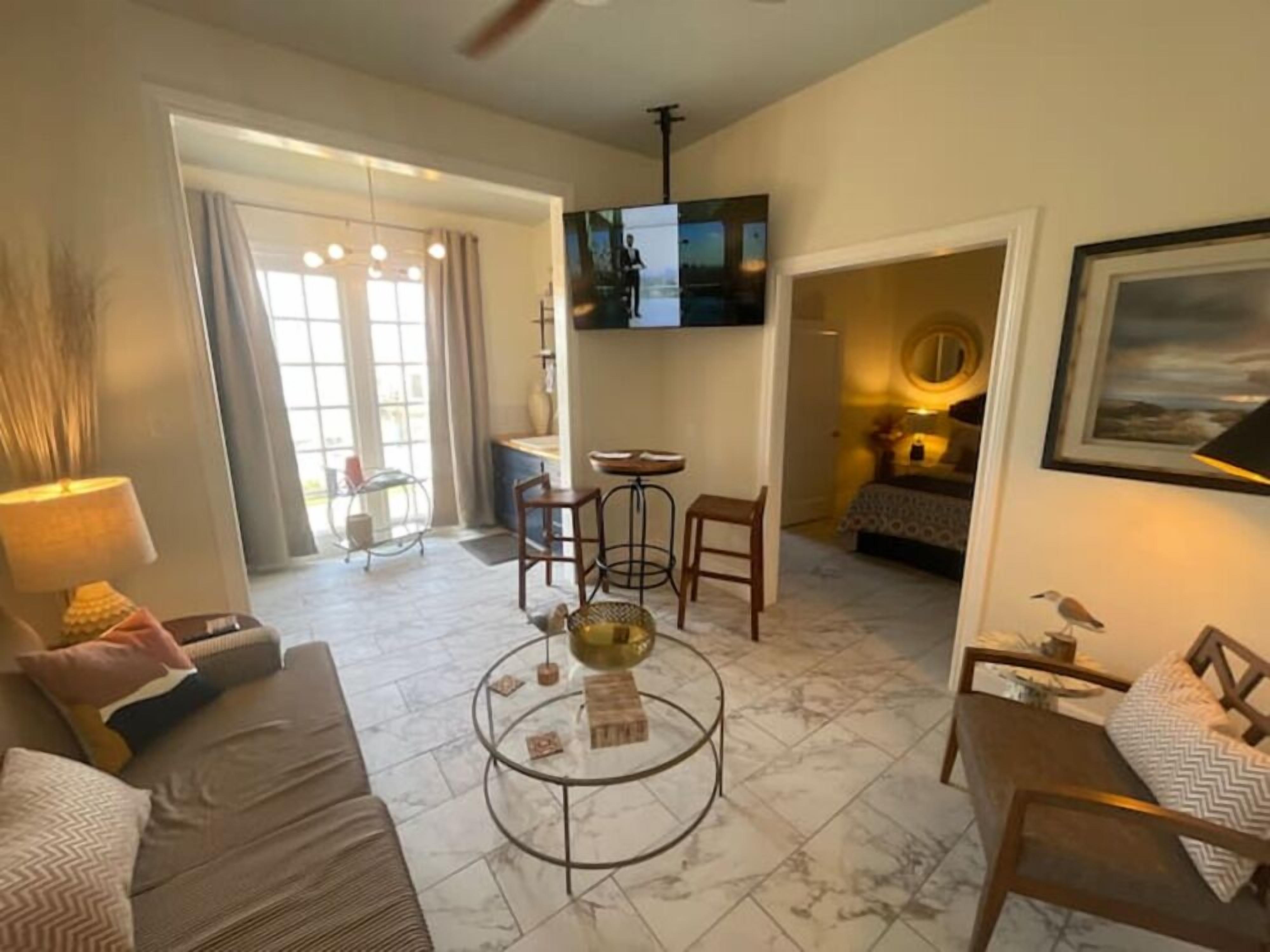A living room with a sofa, coffee table, TV, and a dining area with chairs and a table.