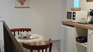 A small kitchen with a microwave, a refrigerator, and a dining area with a table and chairs.