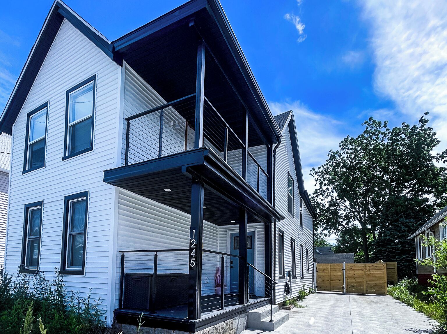 Ein zweistöckiges Haus mit Balkon, Garage und Holzzaun.