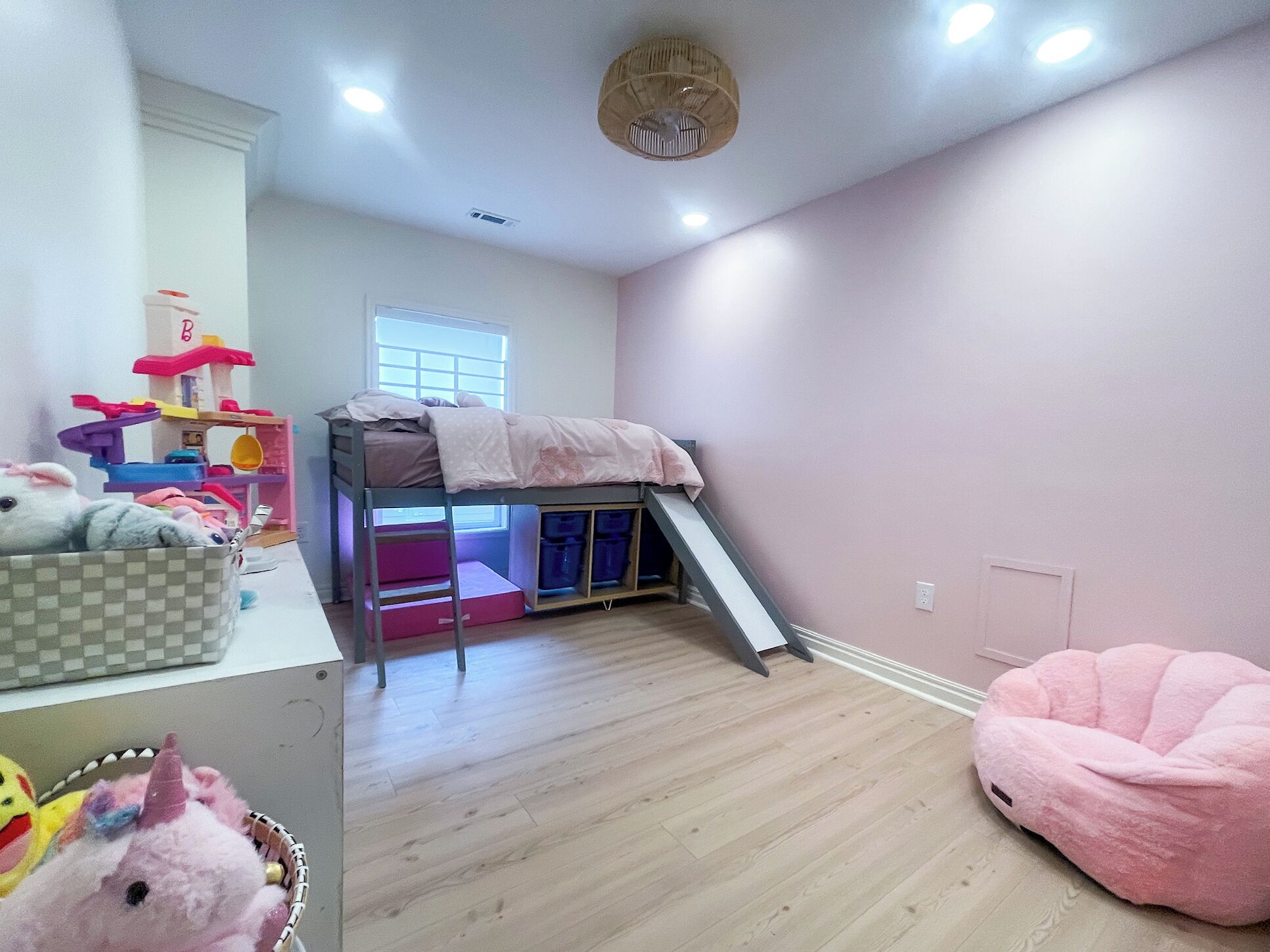 Ein Kinderzimmer mit Etagenbetten, einem Spielbereich und einem rosa Sitzsack.