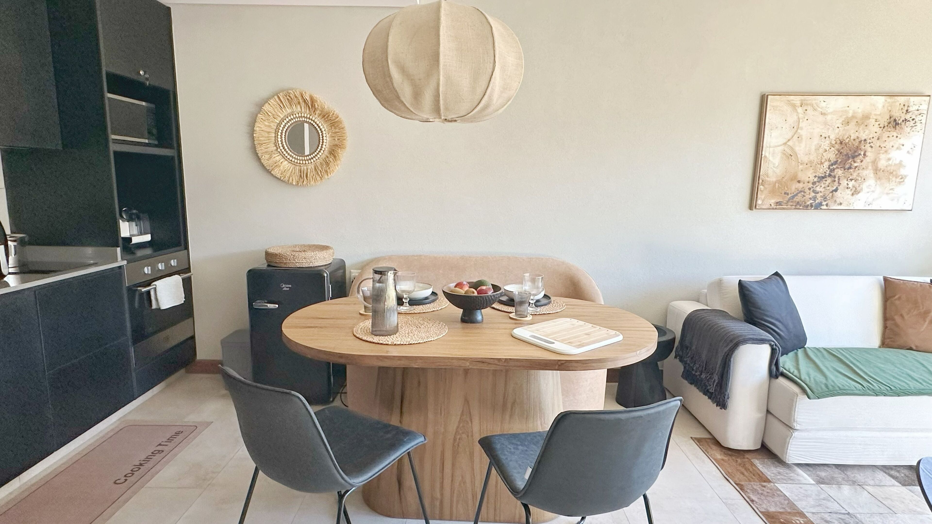 A modern kitchen with a dining area, a sofa, and a painting on the wall.