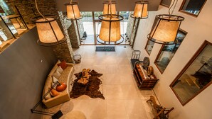 A modern interior with a stone wall, a leather sofa, a wooden coffee table, and hanging lamps.