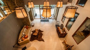 A modern interior with a stone wall, a leather sofa, a wooden coffee table, and hanging lamps.