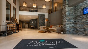 A spacious lobby with a stone wall, a reception desk, a seating area, and a mezzanine level.