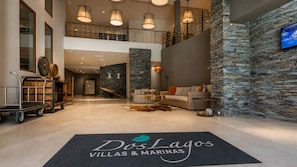 A spacious lobby with a stone wall, a reception desk, a seating area, and a mezzanine level.