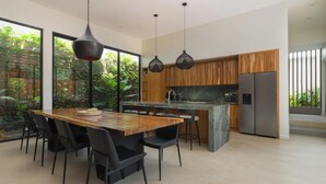 A modern kitchen with a wooden dining table, black chairs, and pendant lights. - Spacious 4-bedroom house with AC in marvelous Playa Langosta (Playa Langosta)