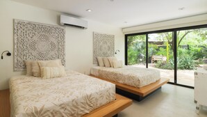 A modern bedroom with two beds, a large window, and a decorative wall panel. - Spacious 4-bedroom house with AC in marvelous Playa Langosta (Playa Langosta)