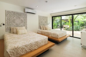 A modern bedroom with two beds, a large window, and a decorative wall panel. - Spacious 4-bedroom house with AC in marvelous Playa Langosta (Playa Langosta)