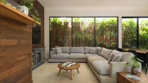A modern living room with a sectional sofa, a wooden coffee table, and a large window with a view of greenery. - Spacious 4-bedroom house with AC in marvelous Playa Langosta (Playa Langosta)
