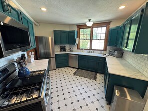 A kitchen with teal cabinets, a stainless steel refrigerator, a microwave, and a gas stove. - Historic 1908 Wamsley House-Completing Renovation! (Hamilton)