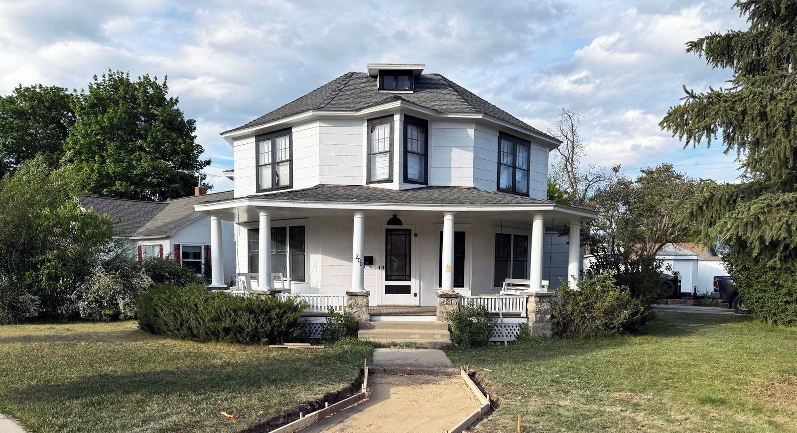 A two-story house with a porch, a front yard, and a driveway.